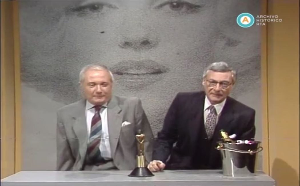 Los reconocidos conductores Rómulo Berruti y Carlos Morelli presentan un episodio de su popular ciclo televisivo "Función Privada", acompañados de un trofeo y una cubeta de hielo.