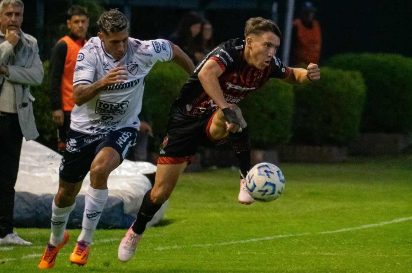 Valentín Pereyra controla la pelota frente a un rival de Quilmes.