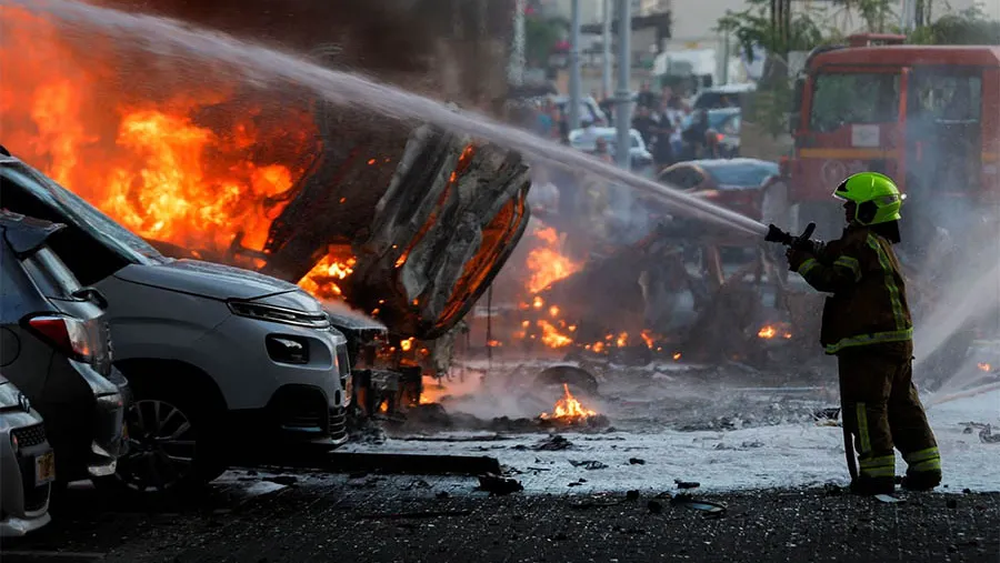 Los lanzamientos de cohetes desde Gaza provocaron innumerables incendios. En la imagen un bombero apaga las llamas de varios vehículos tras el ataque palestino en la ciudad israelí de Ashkelón.