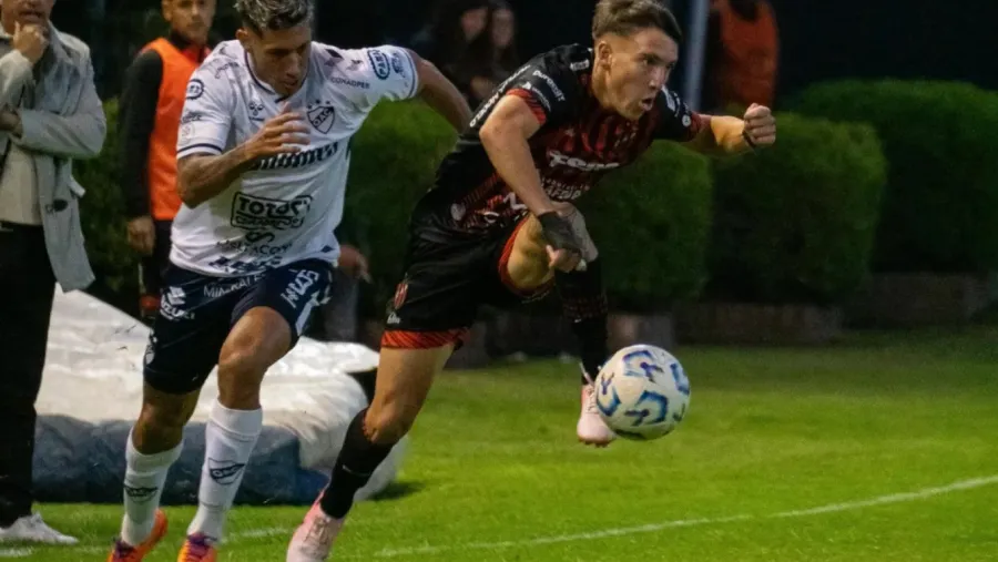 Valentín Pereyra controla la pelota frente a un rival de Quilmes.