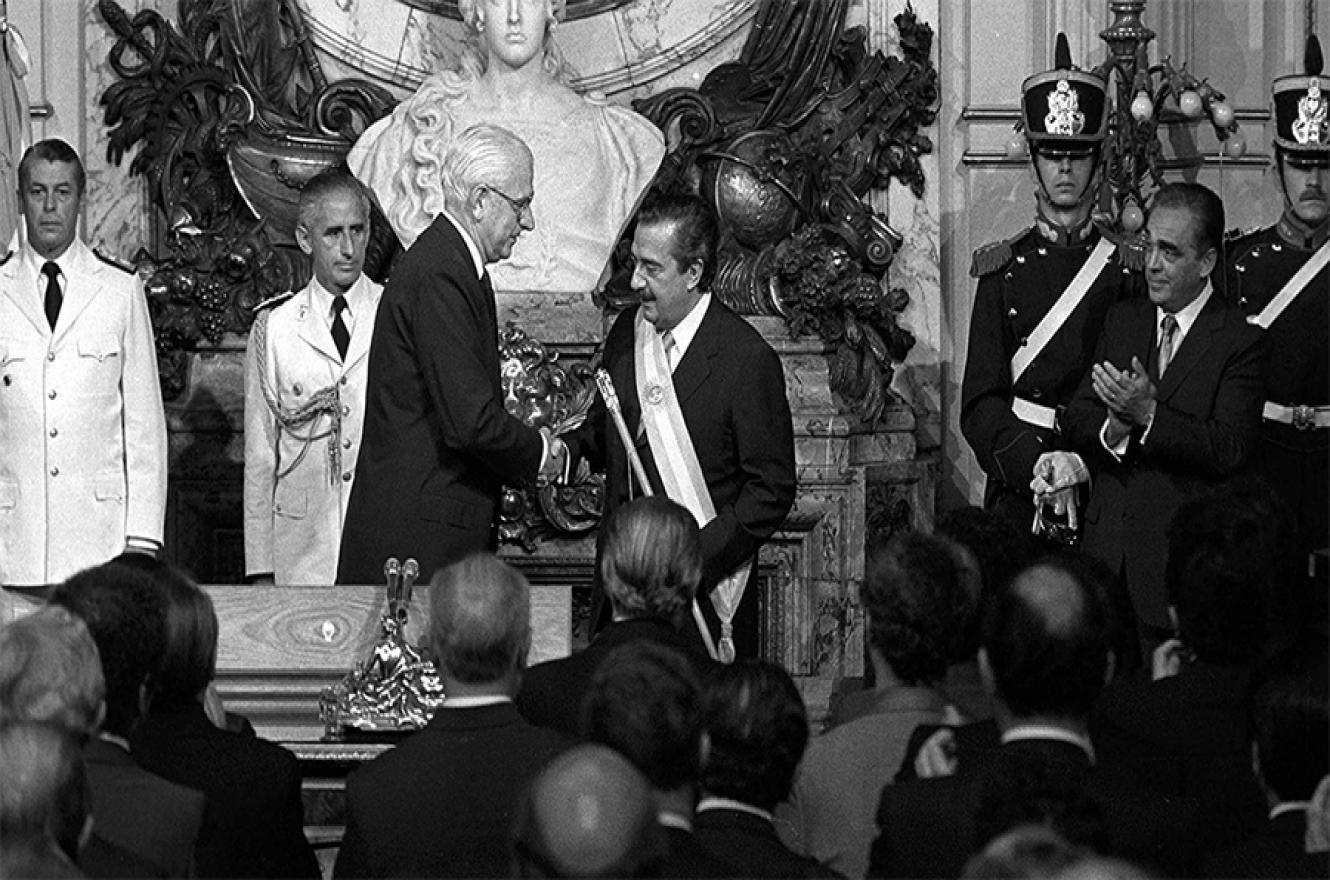 En el salón Blanco de la Casa Rosada, Alfonsín recibía la banda presidencial y el bastón de mando de parte del dictador Reynaldo Bignone, y luego tomó juramentos a sus ministros.