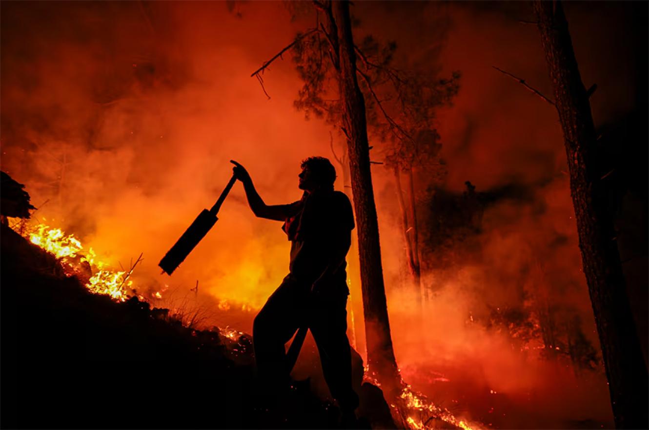 Un hombre parte de un grupo de bomberos y vecinos combate un incendio forestal en Intiyaco, provincia de Córdoba, el 23 de septiembre de 2024.